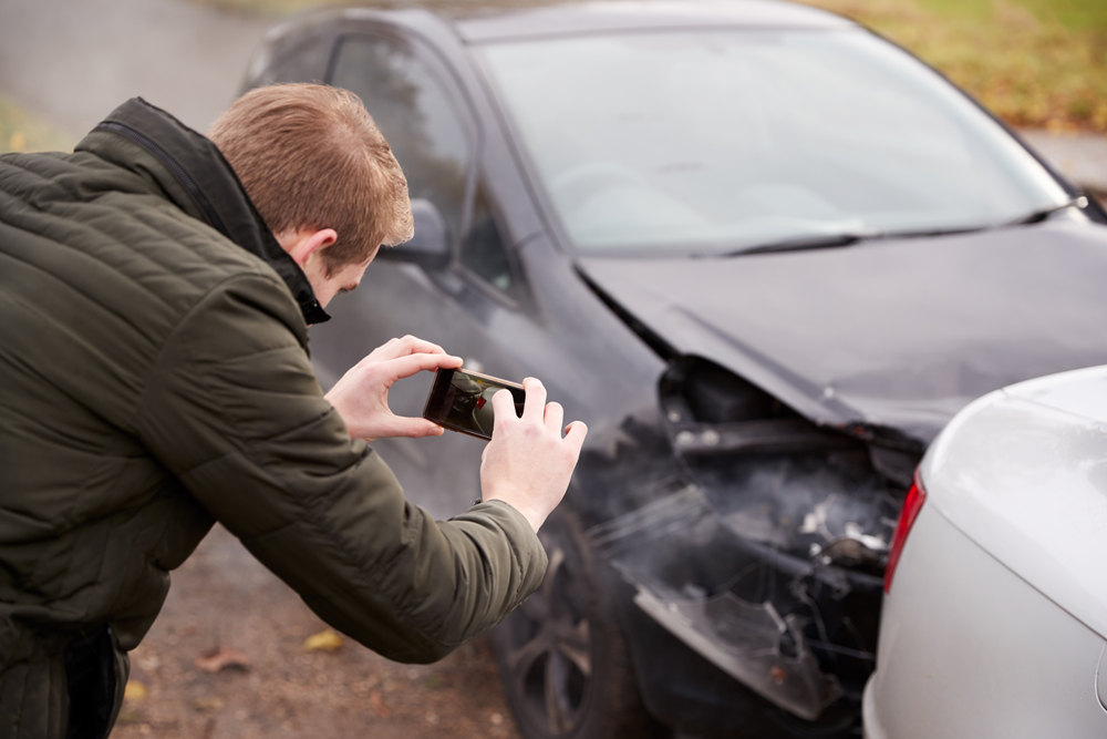 Man Taking Photo Of Car Accident On Mobile Phone