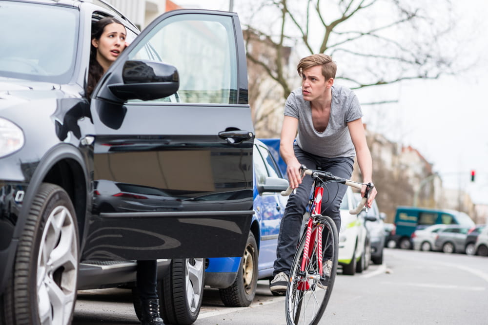Cyclist approaching car door opening causing potential bicycle dooring accident in San Diego